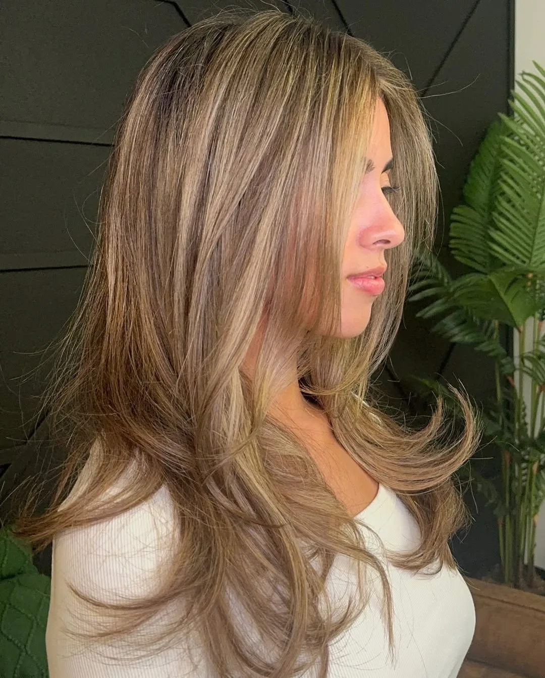 Lived-in bronde colour seen in side profile, soft highlights grown through mid-length waves.